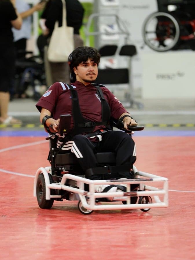 Rolling Rapids athlete in a burgundy UCHealth jersey seated in a sport chair with a white bumper guard at Nu-Venture